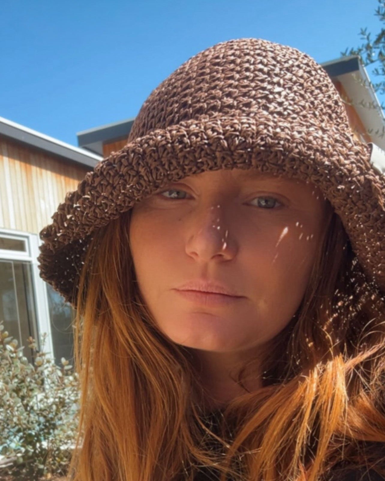 Person wearing a brown knitted hat outdoors on a sunny day